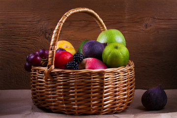 Figs, lemon, lime, plums, grape, blackberries, avocado, apples, pears and peaches in basket. Studio shot of fruits. Fruit still life