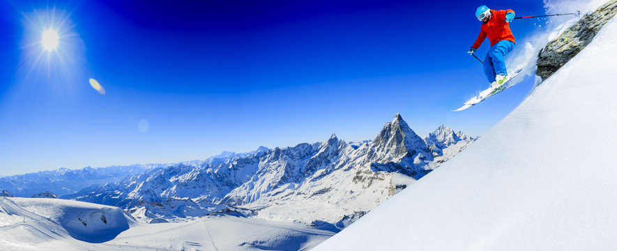 Man jumping from the rock, skiing on fresh powder snow with Matterhorn in background, Zermatt in Swiss Alps.