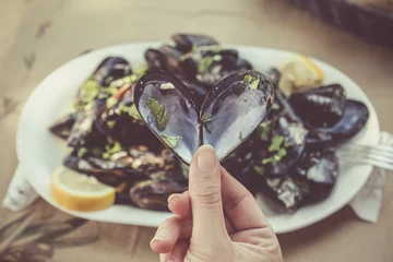 Fototapete Close up of female hand holding opened heart shaped mussel at the restaurant table. Sea food and healthy eating concepts.  © zphoto83