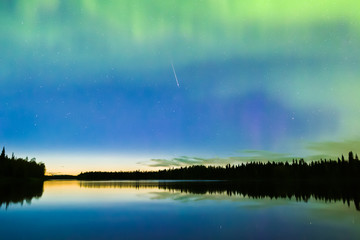 Shooting star and Nortehrn lights on the sky above river