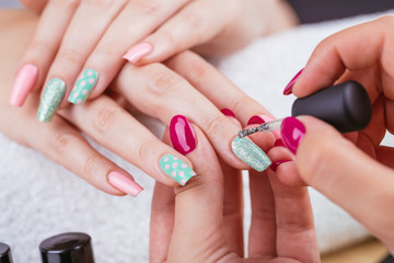 Manicure - Beauty treatment photo of nice manicured woman fingernails. Very nice feminine nail art with nice pink and light green nail polish. Polka dots design. - obrazy, fototapety, plakaty