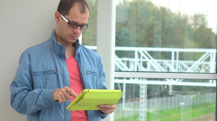 Programmer in glasses using his tablet computer at modern railroad station
