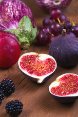 Ripe purple figs, plums, grape, eggplant and onion. Fruit and vegetable still life on wooden background. Clean eating concept. Colorful food collage