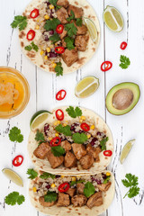 Mexican tacos with quinoa salad, meat, black beans and corn on rustic wooden table. Recipe for Cinco de Mayo party. Top view.
