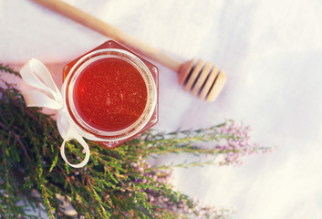 Honey in a glass jar with flowers melliferous herbs on a wooden surface. Honey with flowers of juniper
