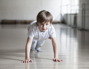 Cute boy in white clothes practicing capoeira (brazilian martial art that combines elements of...