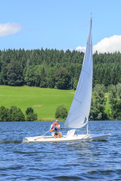 Mann segelt mit einer Jolle auf einem See