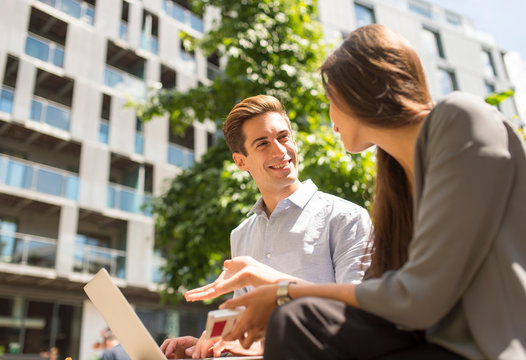 Young businesswoman and man using laptop and chatting, London, UK