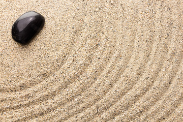 Fototapeta na wymiar Black basalt stone on sand imitating water ripples