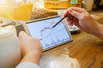Business man works with graph on tablet pc with stylus in cafe