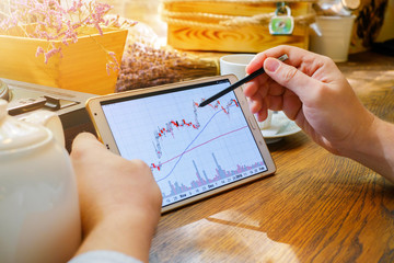 Business man works with graph on tablet pc with stylus in cafe