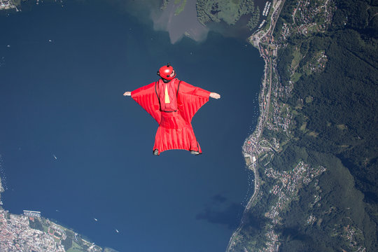 Wingsuit skydiver pilot flying over lake, Locarno, Tessin, Switzerland
