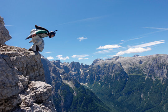 Base jumper preparing to jump from edge of high mountain