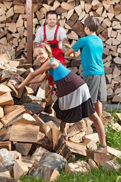 Kids helping their father to stack the chopped firewood