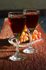 Two glasses of homemade rose wine and grapes on table at garden