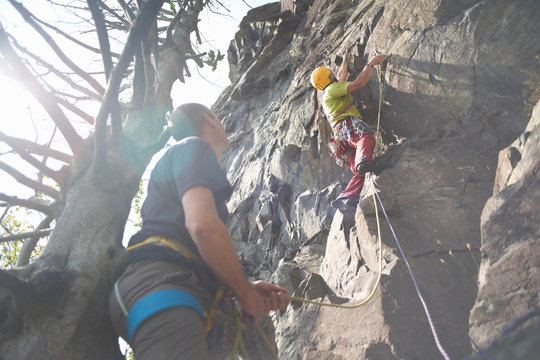Low angle view of friends climbing rock face