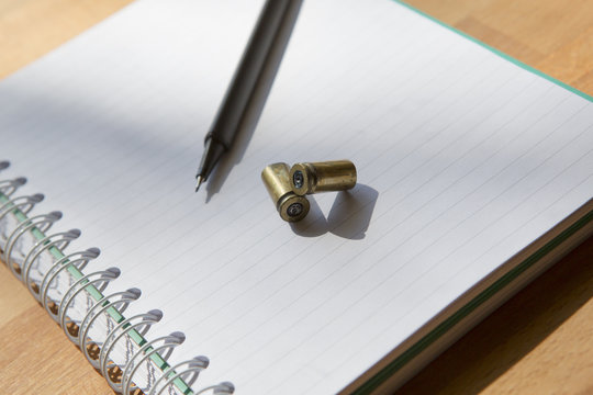 Suicide note. An image of a paper sheet with pen. Couple of empty bullets are on the paper.