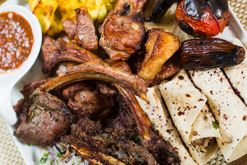 Plate of arabic kebab meat with potato, tomatoes and pita.