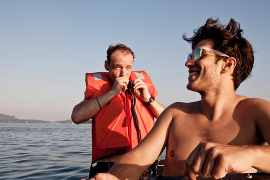 Man on sailboat wearing lifejacket, Capo Testa, Gallura, Sardinia, Italy