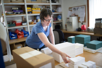 Female worker packing stacked paper in printing press workshop