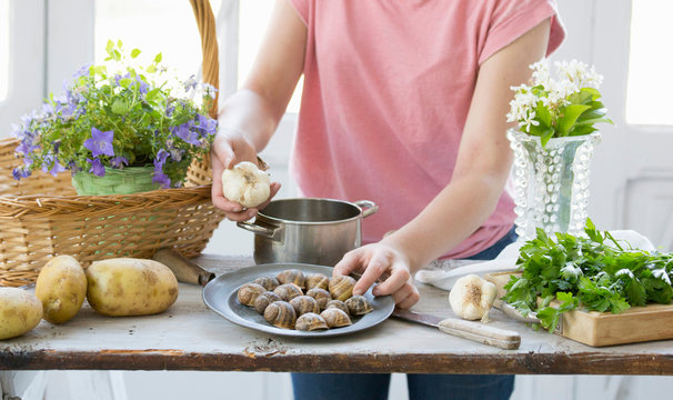 Young woman preparing snails and garlic at kitchen counter, Vogogna,Verbania, Piemonte, Italy