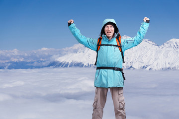 Fototapeta na wymiar Happy male mountaineer man with raised arms. In background high mountains above clouds .