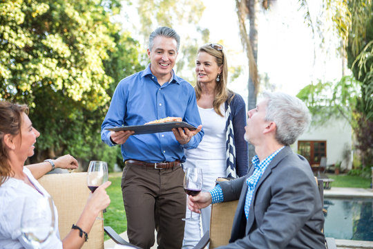 Mature man serving fish cuisine at garden party