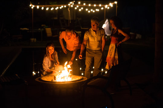Mature adult couples  toasting marshmallows on patio fire at night