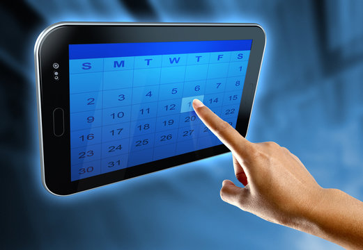 A woman's finger selects a day on a calendar on a digital  tablet