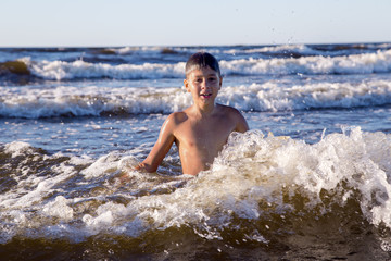 Pretty teenager playing in foamy waves of the Baltic Sea in Jurmala, Latvia