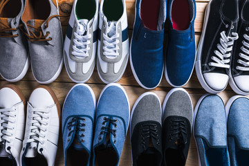 Various pairs of  sneakers laid on the wooden floor background