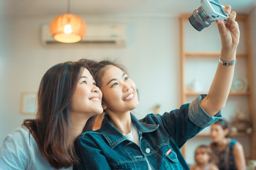 Portrait of two happy young Asian woman take selfie in cozy coff