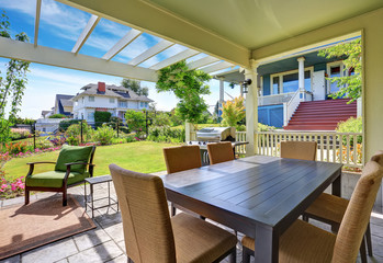 Covered patio area with outside chairs in the backyard garden. House exterior.