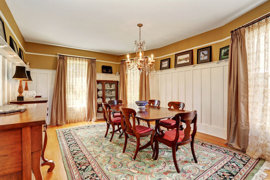Traditional dining room interior with antique furniture and rug.