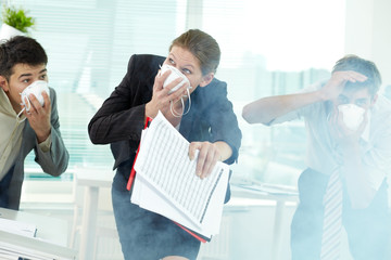 Three business people in gas masks gasping in office