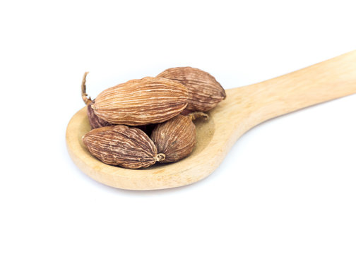 Black Cardamom (Tsaoko Fruit) on wooden spoon over white background