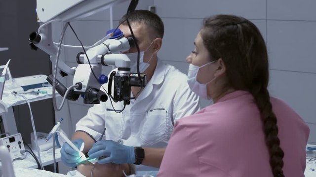 Dentist with assistant treat sick tooth of the patient