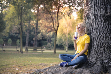 Obraz premium Blonde woman drinking at the park