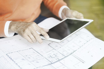 Man with tablet and construction plan, partial view