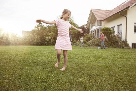 Girl dancing in garden with family in background