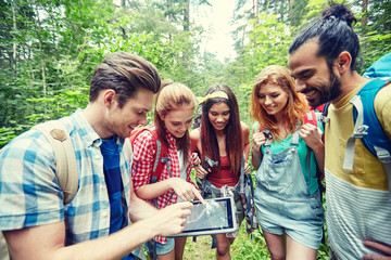 happy friends with backpacks and tablet pc hiking