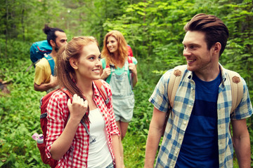 group of smiling friends with backpacks hiking