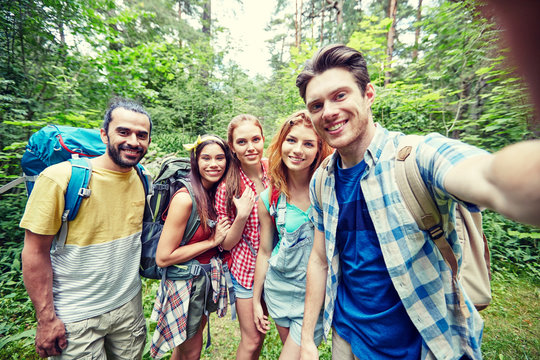 friends with backpack taking selfie in wood