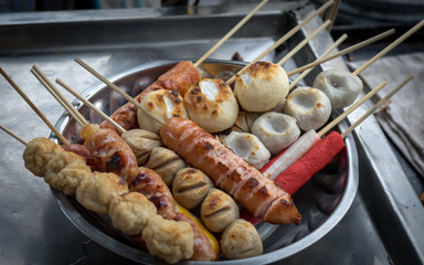 Several Thai meat ball and sausage with bamboo stick in dish.