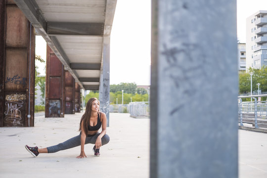 Young woman stretching under bridge