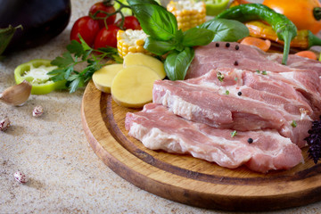 Fresh raw meat pork tenderloin with vegetables on a cutting boar