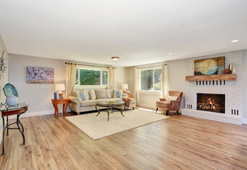 Open floor plan living room interior in white tones with hardwood floor.
