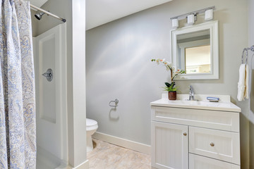 Adorable bathroom interior with white vanity cabinet, tile floor and nice shower curtain.