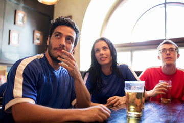 fans or friends watching football at sport bar