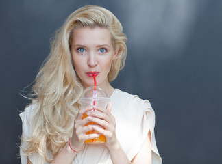 Beautiful sexy blonde with blue eyes drinking beverage through a straw on a hot summer day near the...